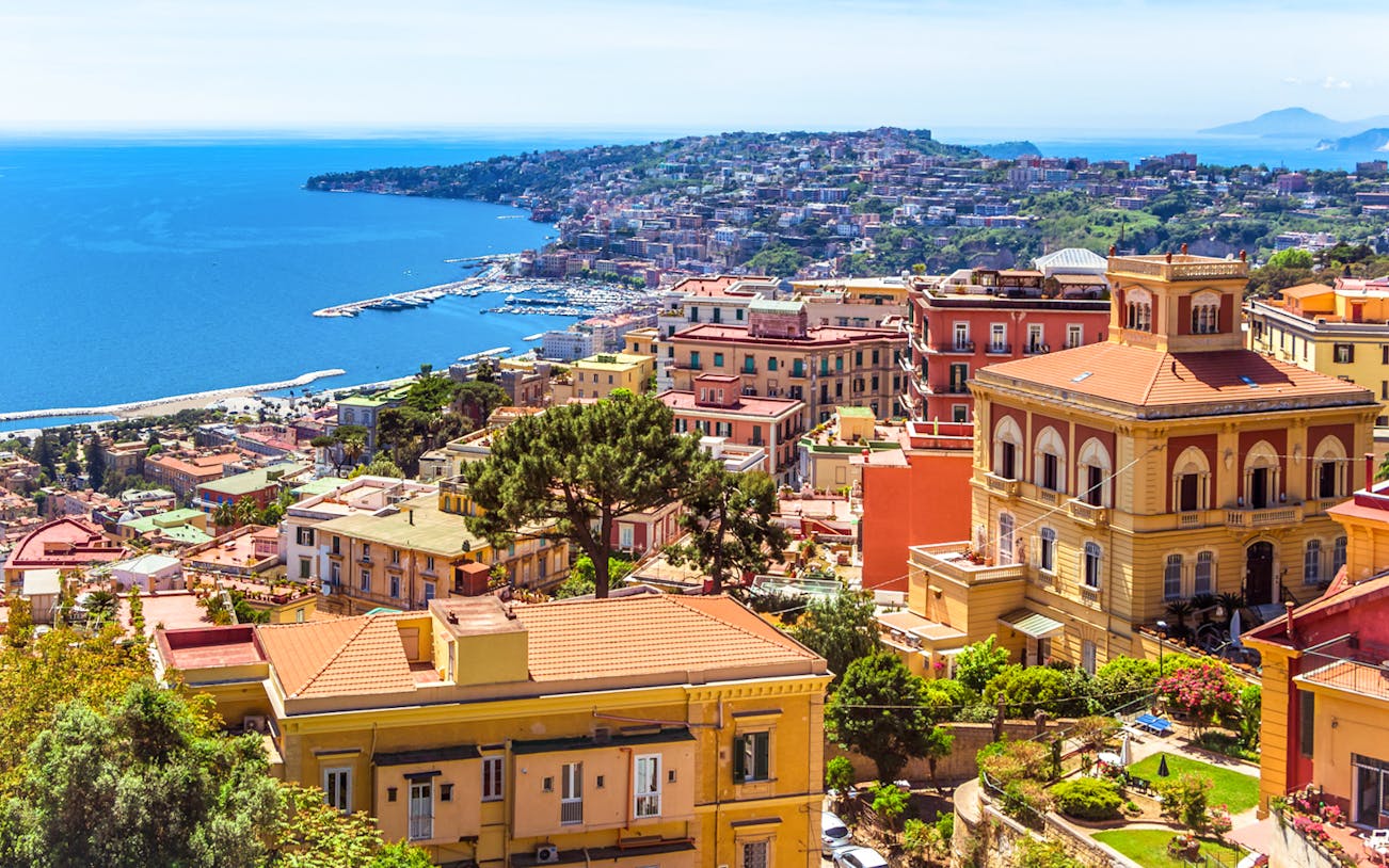 Naples cityscape with colorful buildings and coastline, view from above.