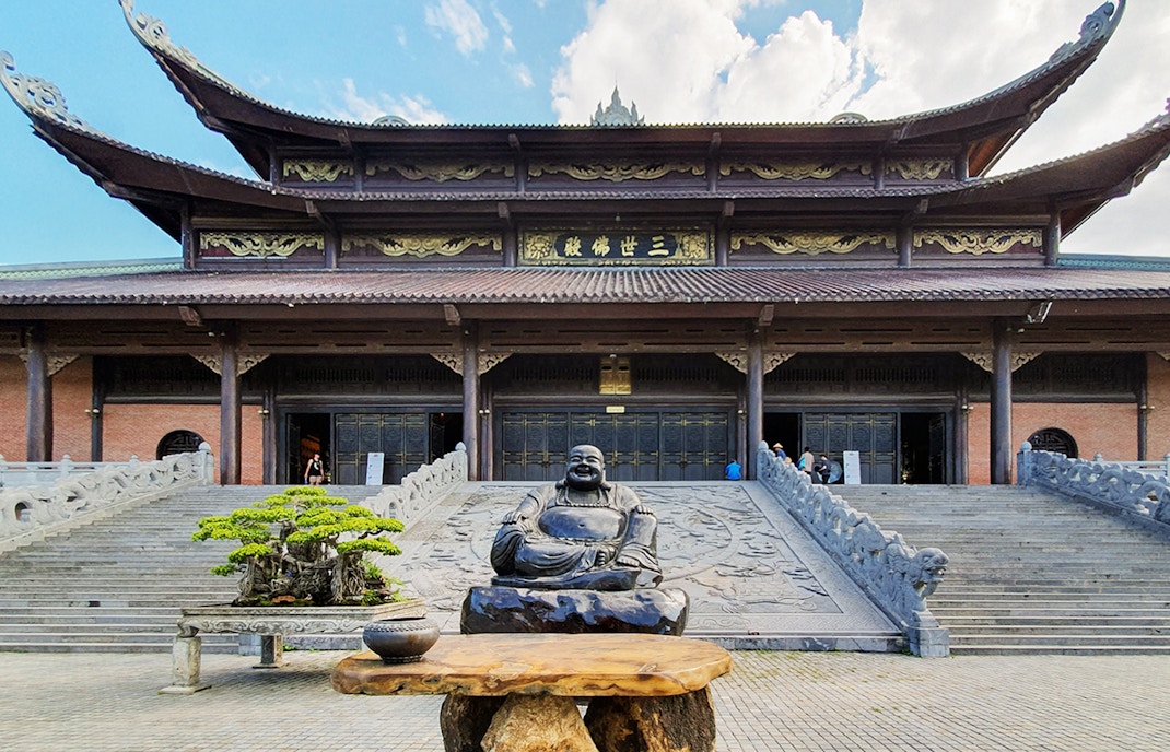 Buddha statue and bonsai tree at Bái Đính Pagoda entrance, Ninh Bình Province, Vietnam.