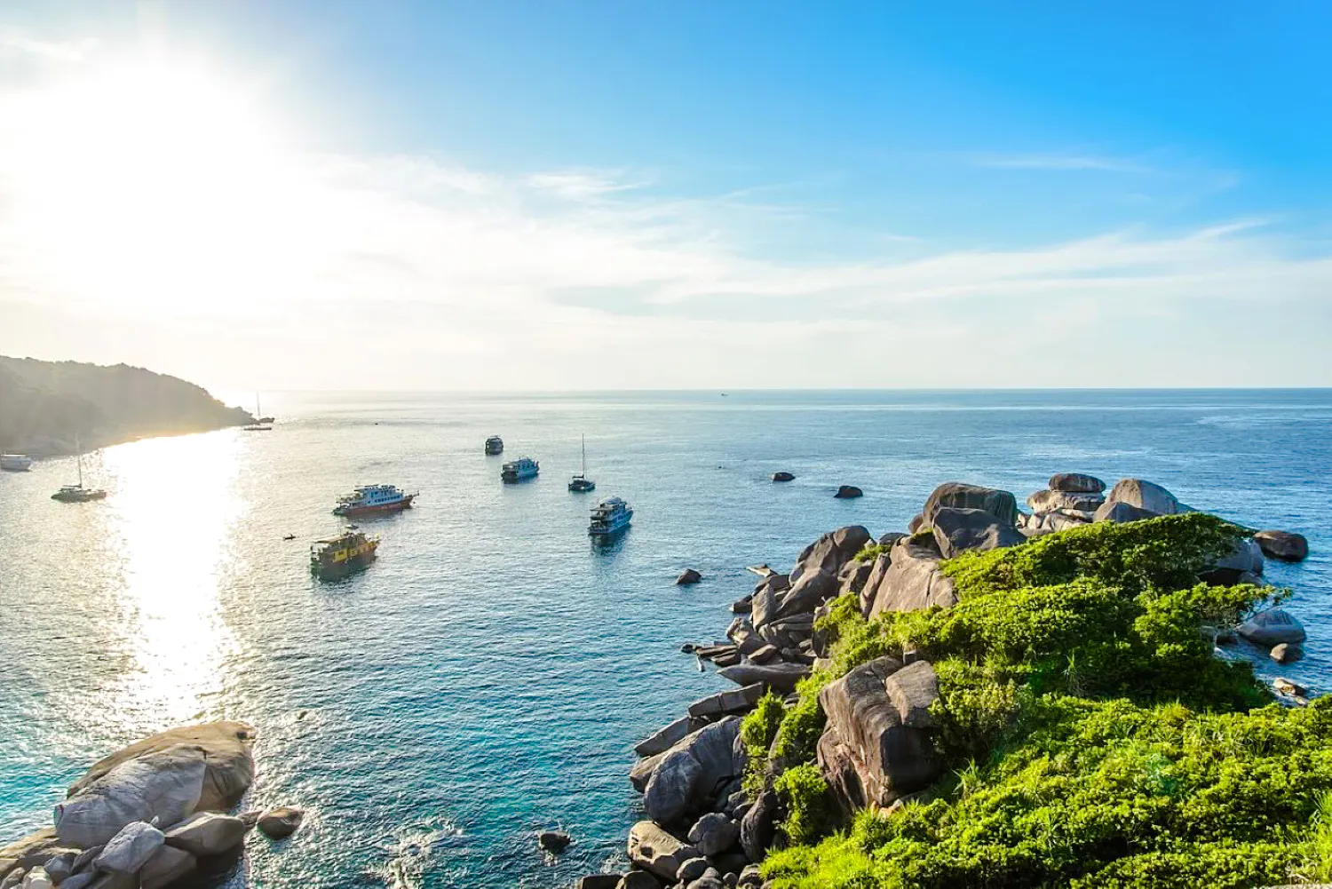 Speedboats near rocky coastline and clear waters of Surin Islands, Krabi.