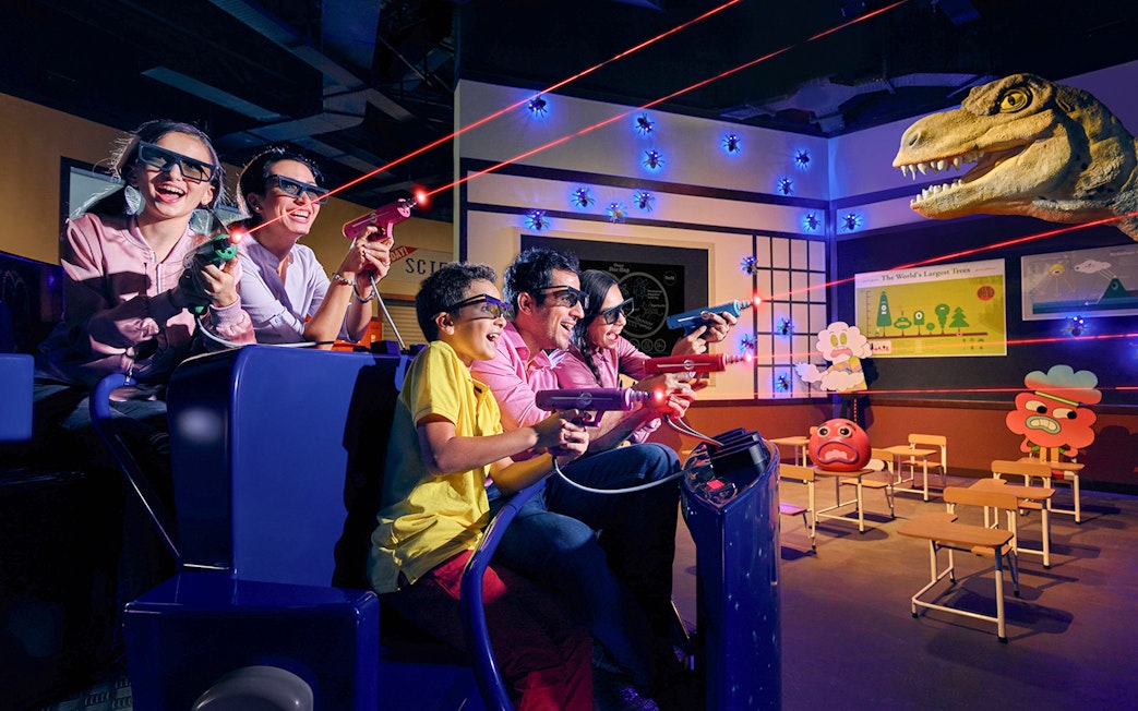 Visitors enjoying a 3D dinosaur-themed ride at IMG Worlds of Adventure in Dubai.