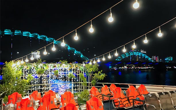 My Xuan Cruise deck on Han River at night with city lights and bridge in view.