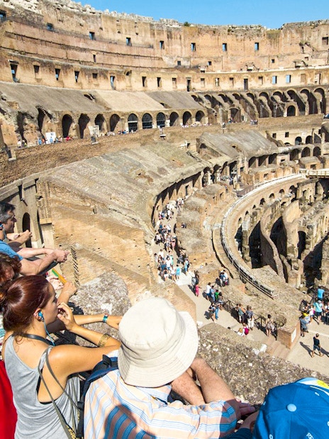 Tourists with a guide overlooking the interior of the Colosseum in Rome, Italy.