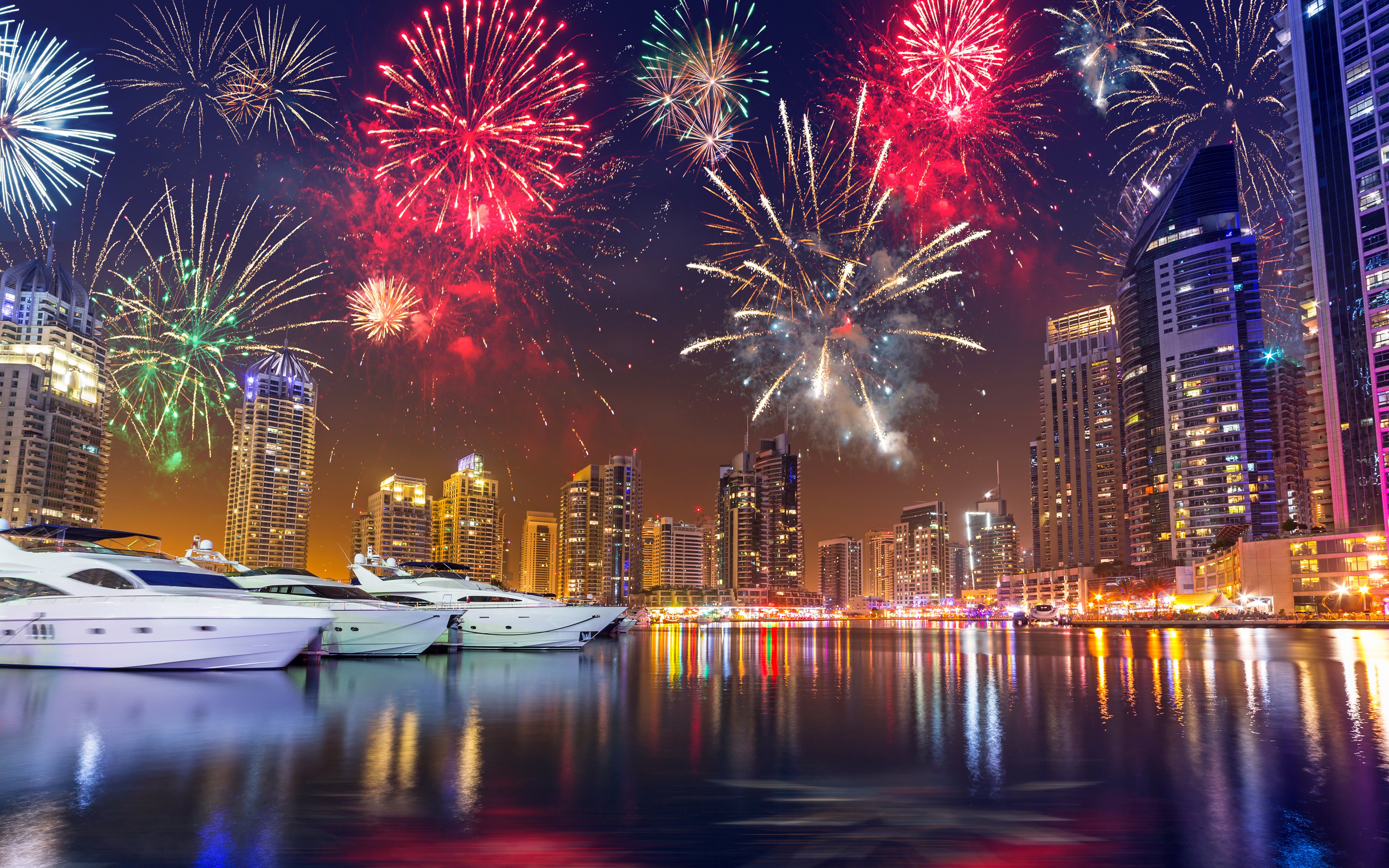 Fireworks over Dubai Marina skyline with yachts on the water, UAE.