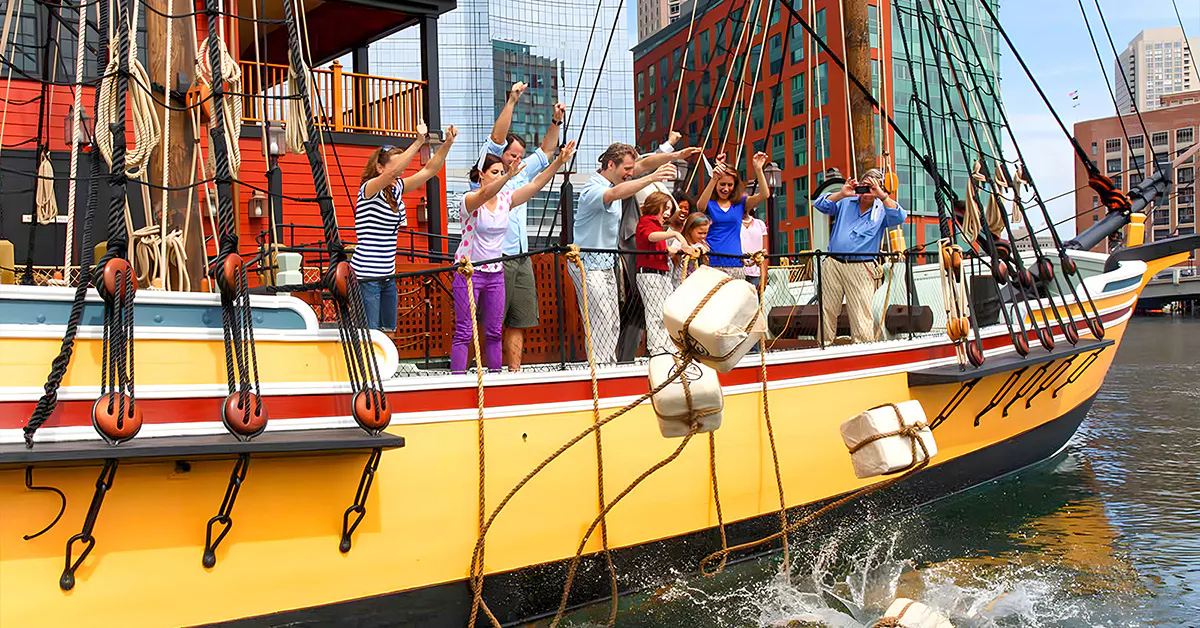 Tourists reenacting Boston Tea Party by throwing tea chests from a ship in Boston Harbor.