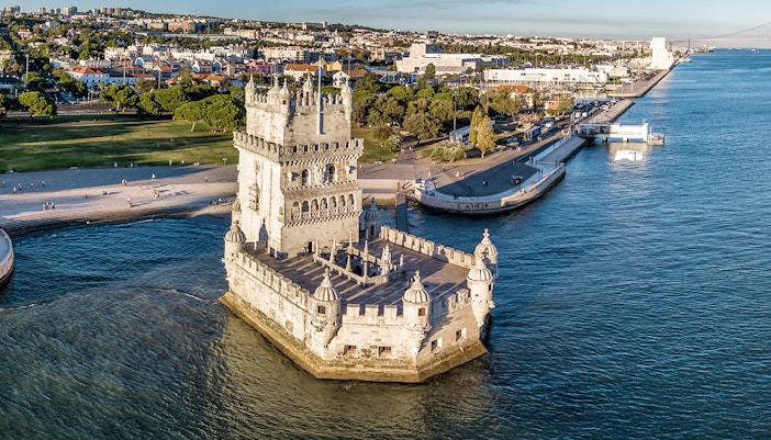 Belem Tower in Lisbon, Portugal, surrounded by water with cityscape in the background.
