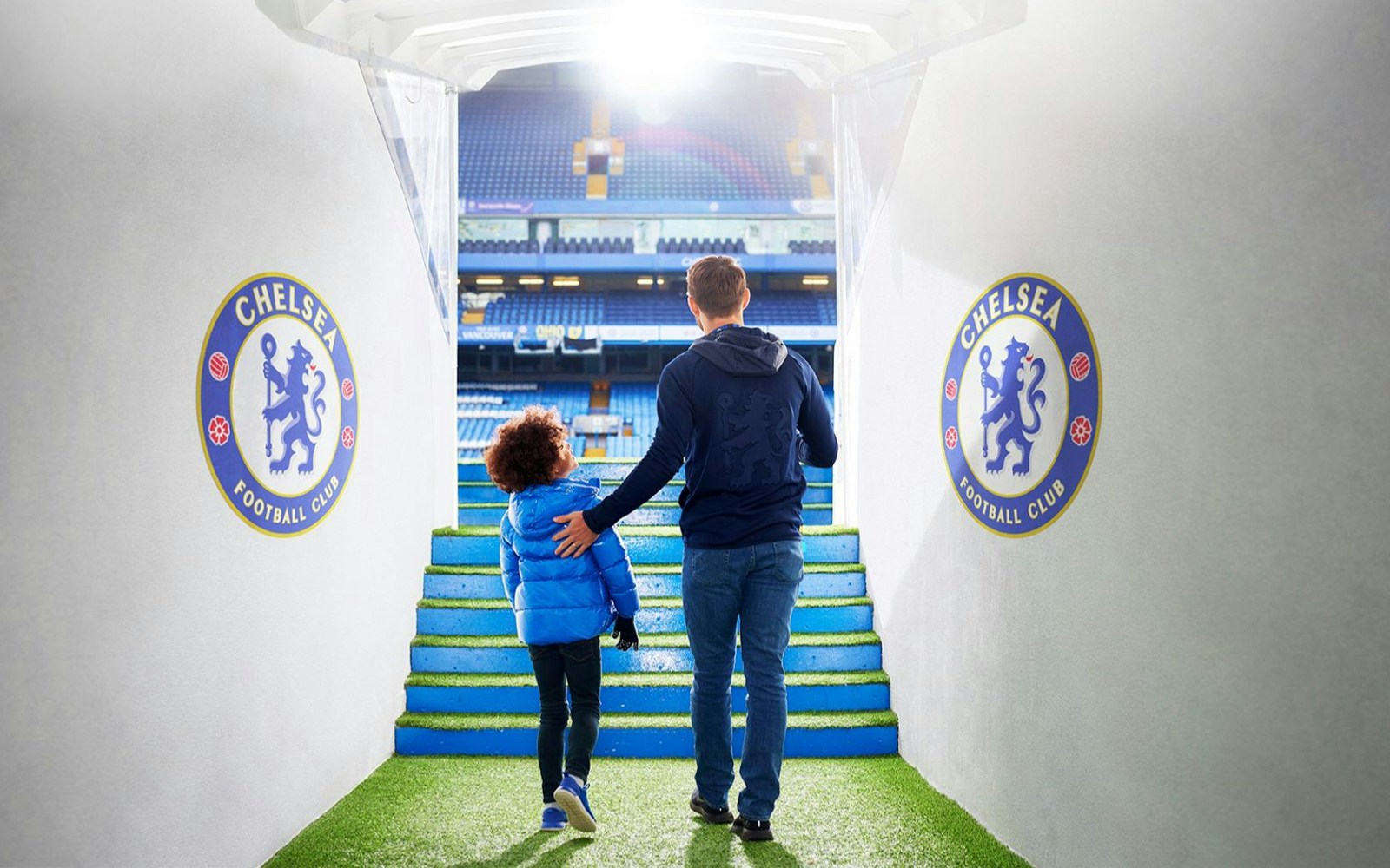 Father and child walking through Chelsea FC tunnel towards the stadium.