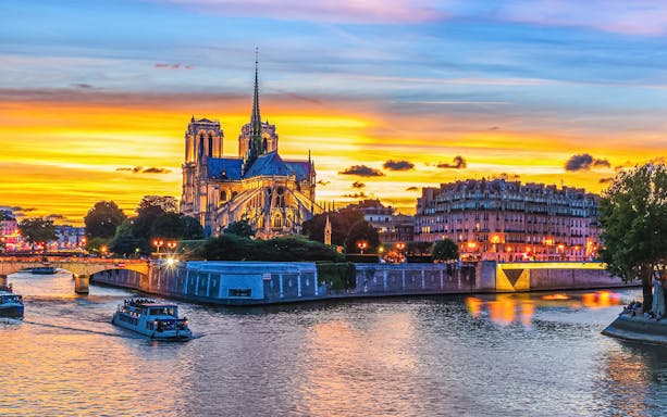 Notre Dame Cathedral at sunset with boats on the Seine River, Paris.