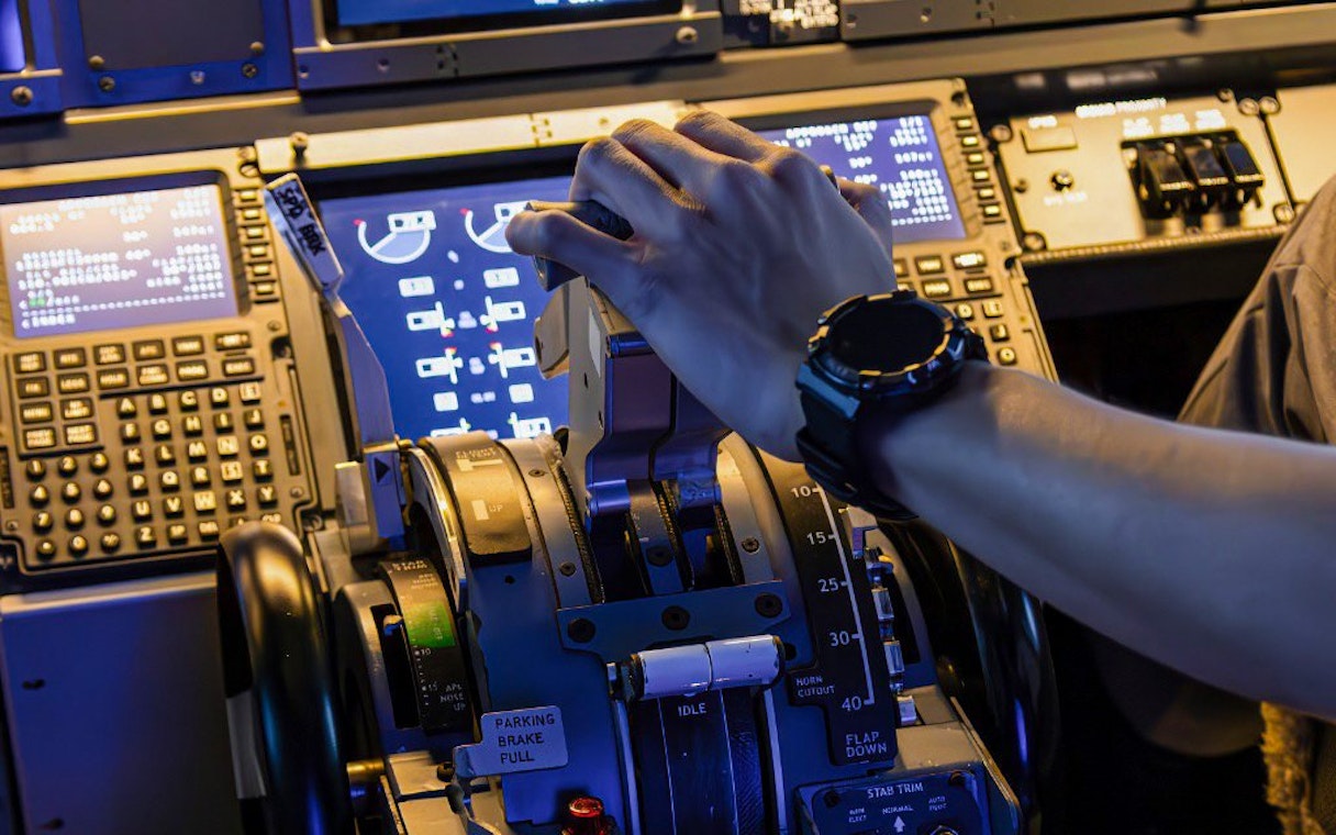 Hand operating controls in a Boeing 737 cockpit during flight experience.