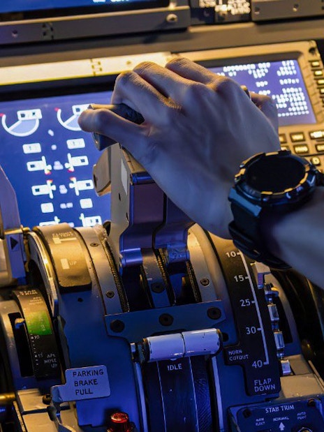 Hand operating controls in a Boeing 737 cockpit during flight experience.