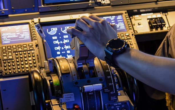 Hand operating controls in a Boeing 737 cockpit during flight experience.