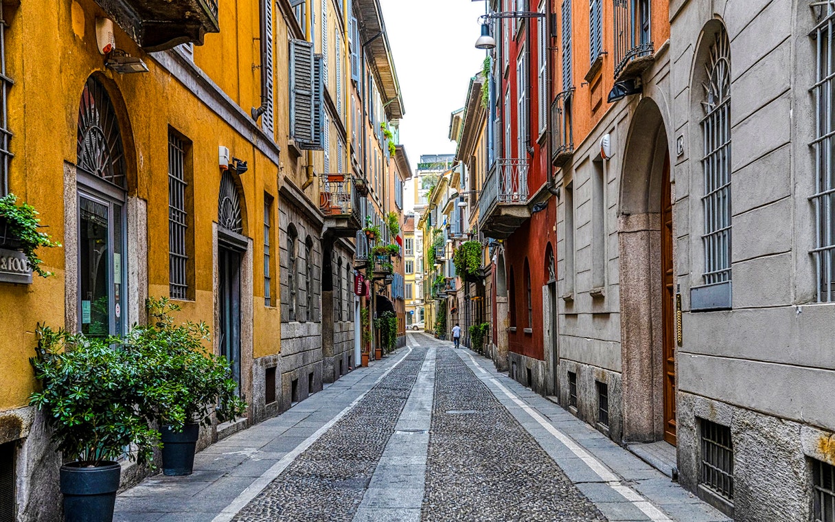 Narrow cobblestone street in Brera District, Milan, lined with colorful historic buildings.