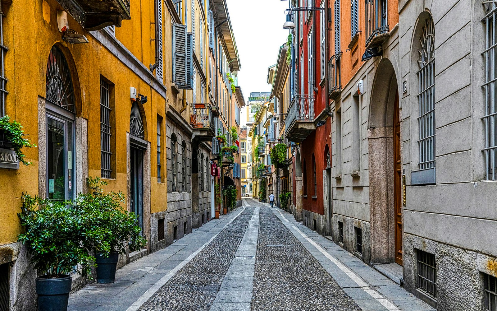 Narrow cobblestone street in Brera District, Milan, lined with colorful historic buildings.