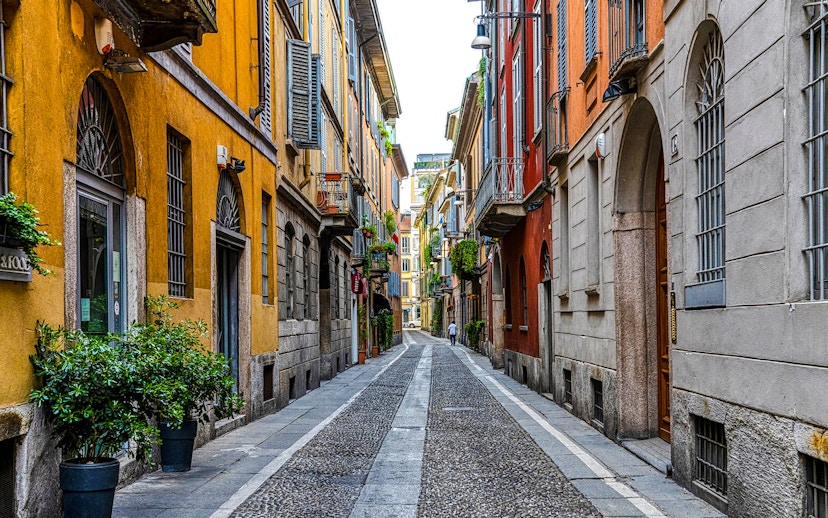 Narrow cobblestone street in Brera District, Milan, lined with colorful historic buildings.