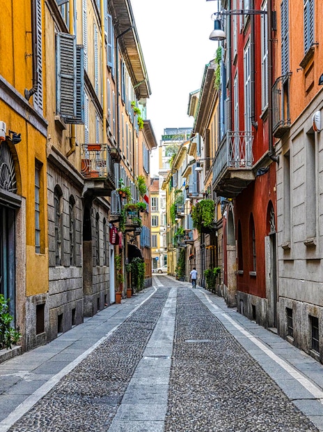 Narrow cobblestone street in Brera District, Milan, lined with colorful historic buildings.