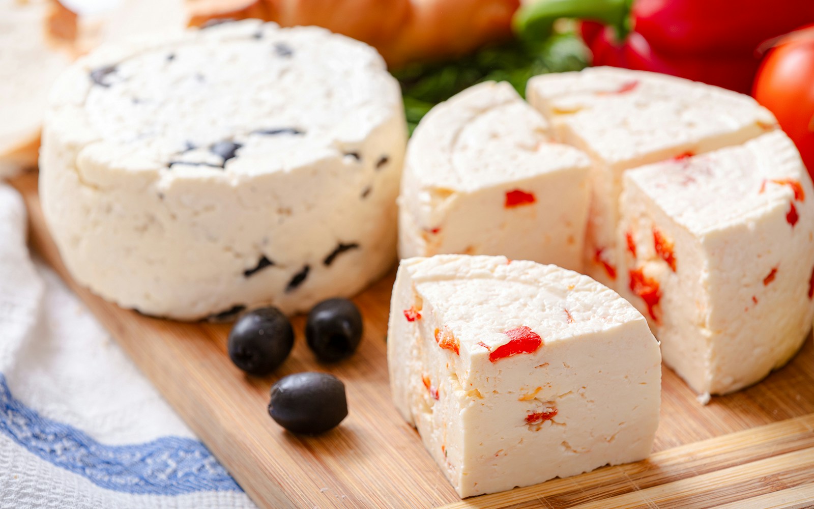 Local Arachova cheese with olives and peppers on a wooden board.