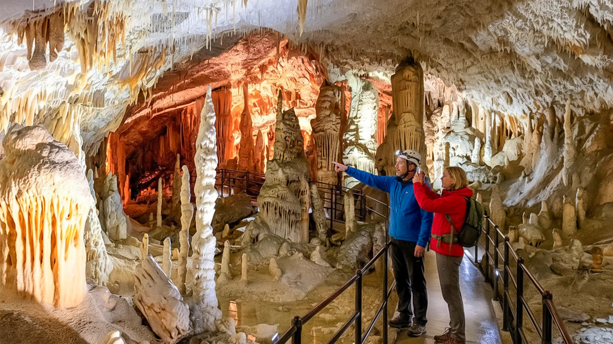 Tour guide with tourist exploring stalactites in Postojna Cave, Slovenia.