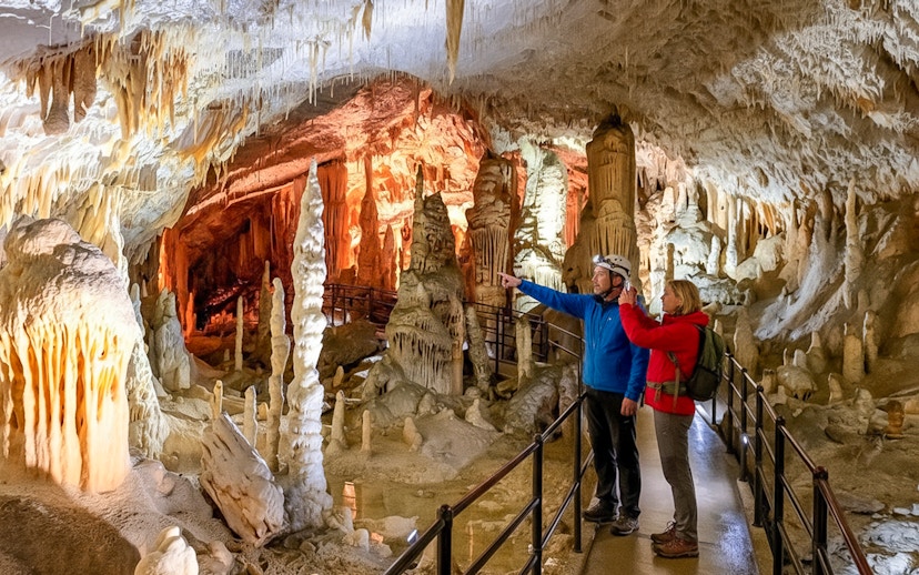 Tour guide with tourist exploring stalactites in Postojna Cave, Slovenia.