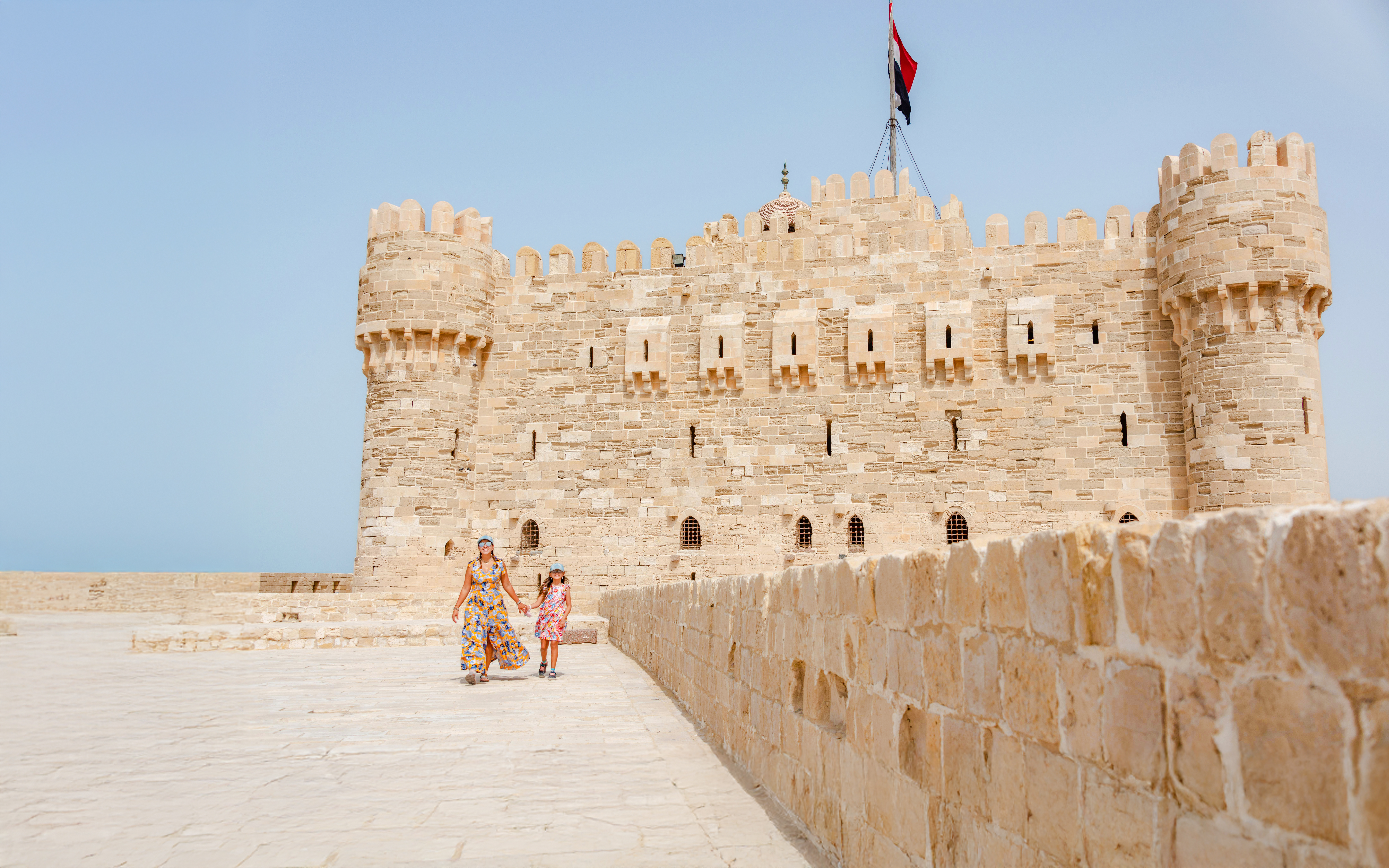 Tourist family exploring Qaitbay Citadel, Alexandria, with historic stone walls and coastal views.