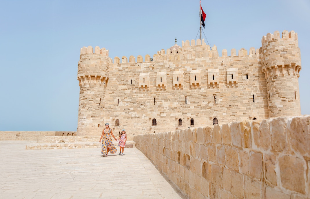 Tourist family exploring Qaitbay Citadel, Alexandria, with historic stone walls and coastal views.