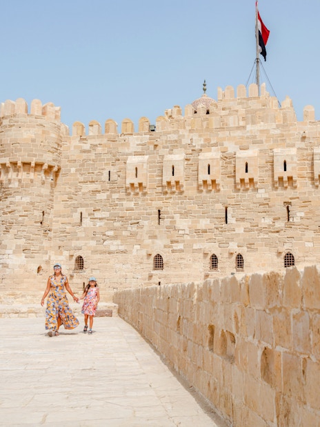 Tourist family exploring Qaitbay Citadel, Alexandria, with historic stone walls and coastal views.