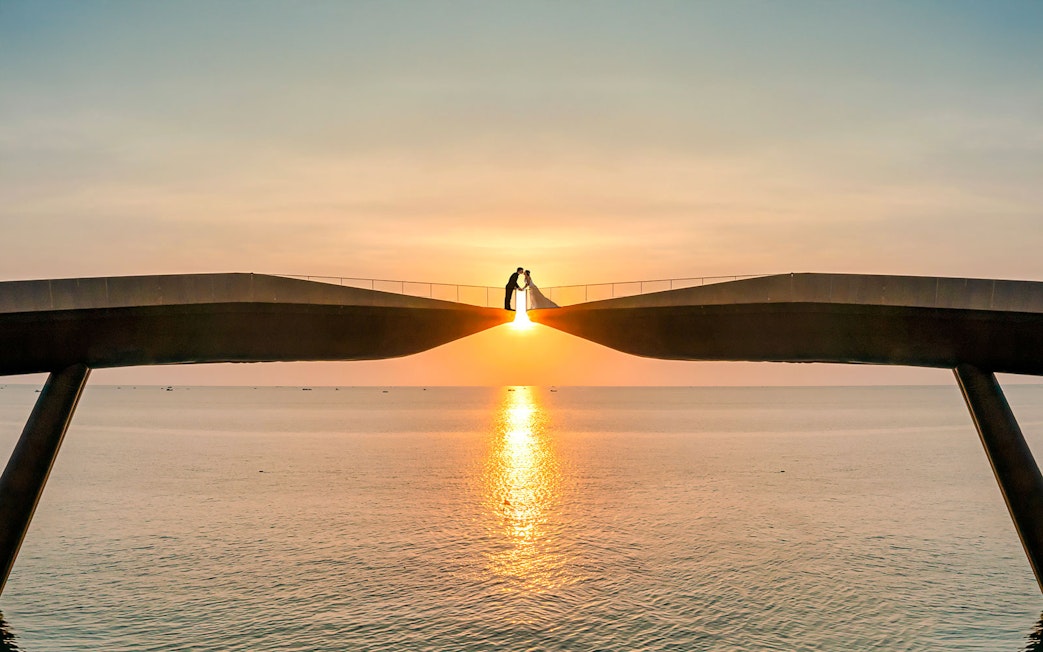 Couple on Kiss Bridge at sunset, Phu Quoc Island, Vietnam.