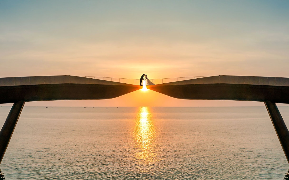 Couple on Kiss Bridge at sunset, Phu Quoc Island, Vietnam.