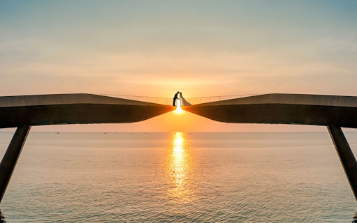 Couple on Kiss Bridge at sunset, Phu Quoc Island, Vietnam.