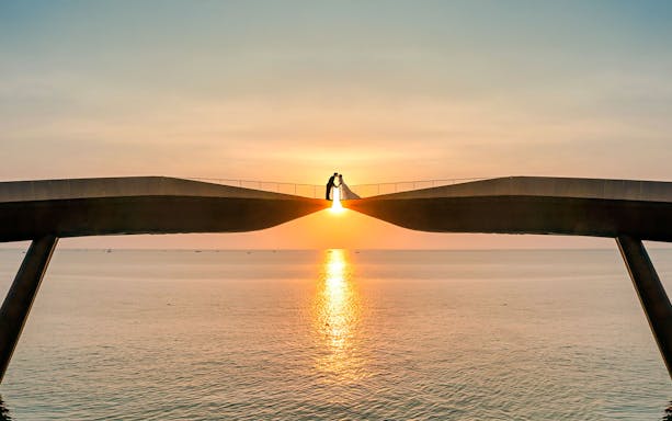 Couple on Kiss Bridge at sunset, Phu Quoc Island, Vietnam.