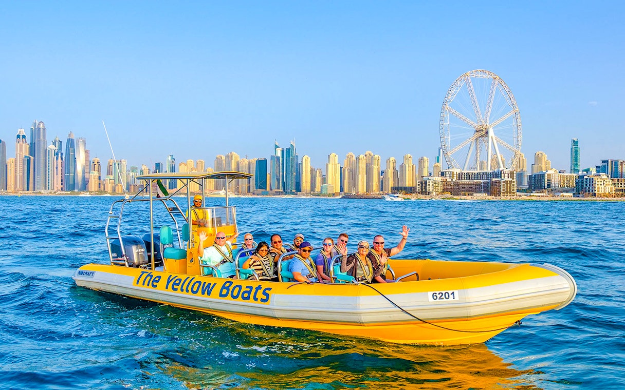 Speedboat tour in Dubai Marina with city skyline and Ferris wheel in background.