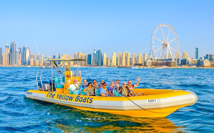 Speedboat tour in Dubai Marina with city skyline and Ferris wheel in background.