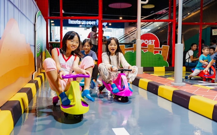Kids riding toy cars at Tayo Station indoor playground.