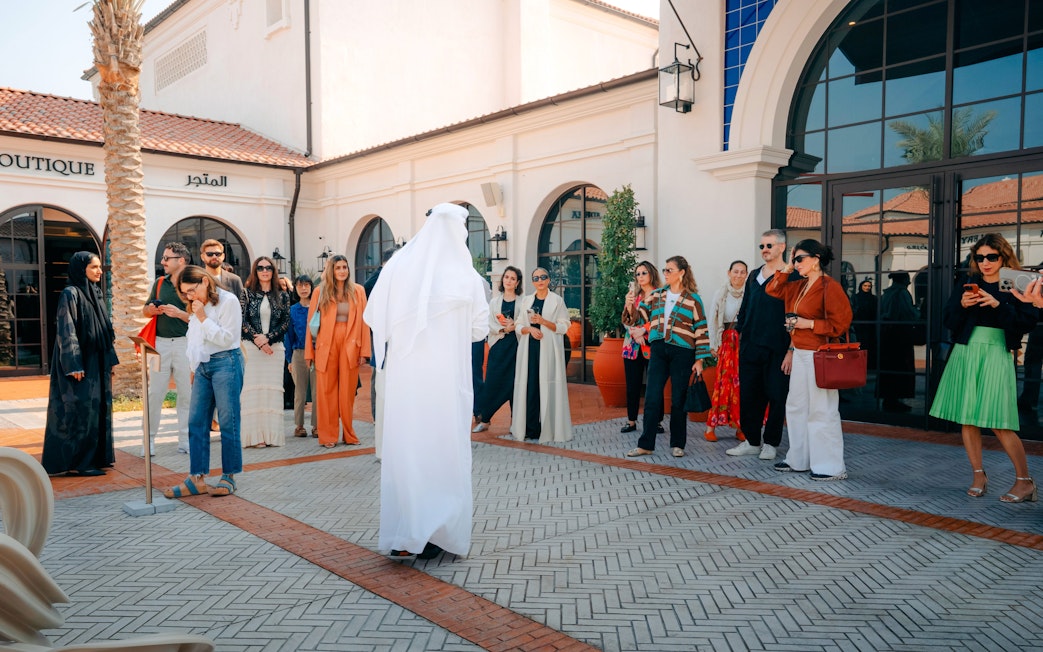 Tour group at Abu Dhabi Royal Equestrian Arts, guide in traditional attire leading.