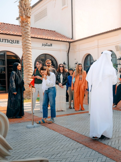 Tour group at Abu Dhabi Royal Equestrian Arts, guide in traditional attire leading.