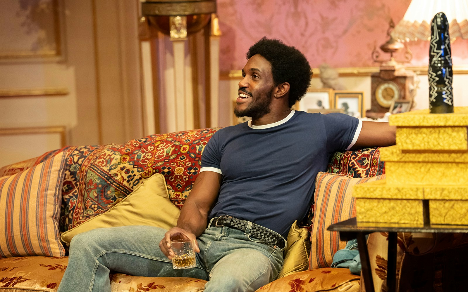 Man relaxing on a patterned sofa with a drink, related to Backstairs Billy.
