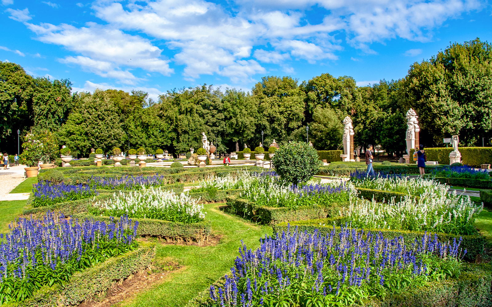 Borghese Gardens with vibrant flower beds and statues in Rome.