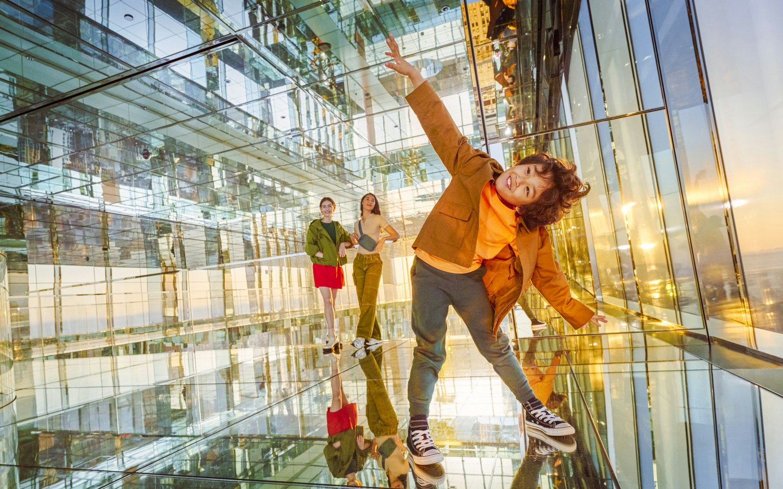 Three people inside SUMMIT One Vanderbilt observation deck, New York City, enjoying panoramic skyline views.