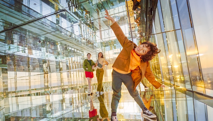 Three people inside SUMMIT One Vanderbilt observation deck, New York City, enjoying panoramic skyline views.