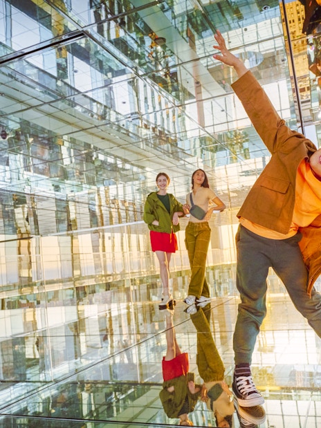 Three people enjoying the mirrored interior of SUMMIT One Vanderbilt observation deck, New York City.
