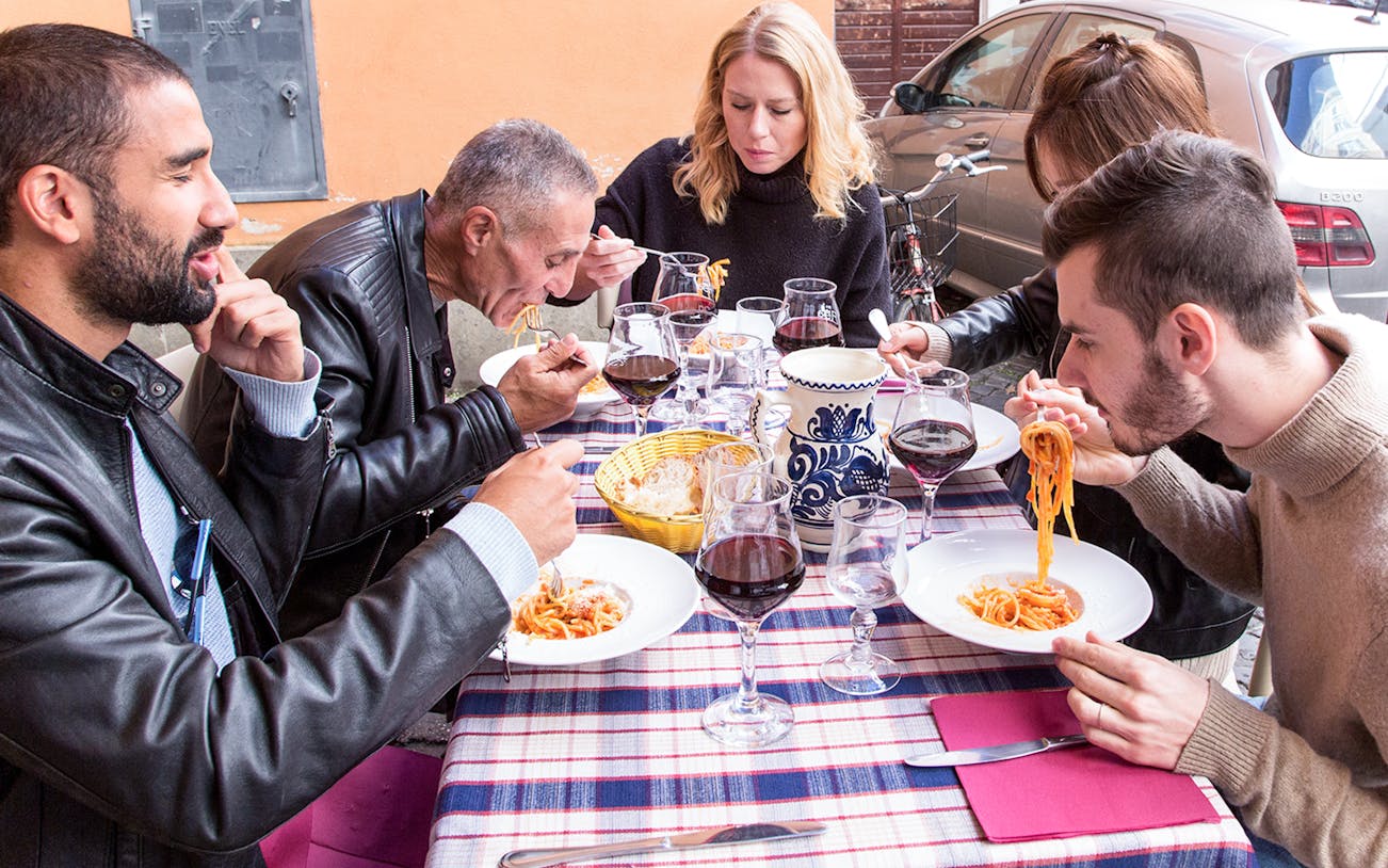 Friends enjoying pasta at an outdoor restaurant in Rome.