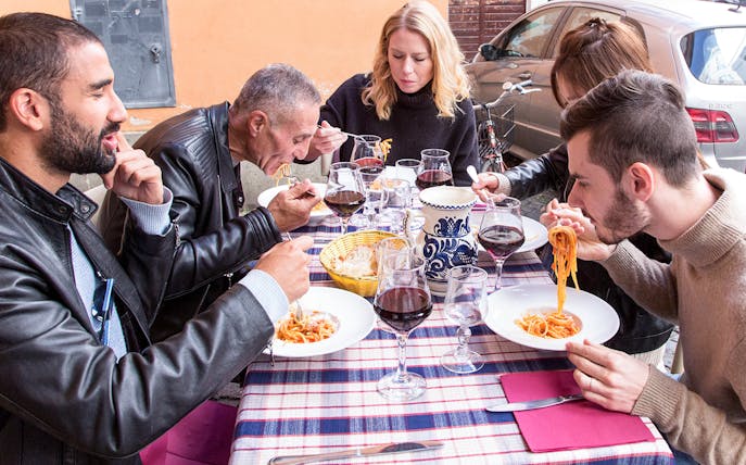 Friends enjoying pasta at an outdoor restaurant in Rome.