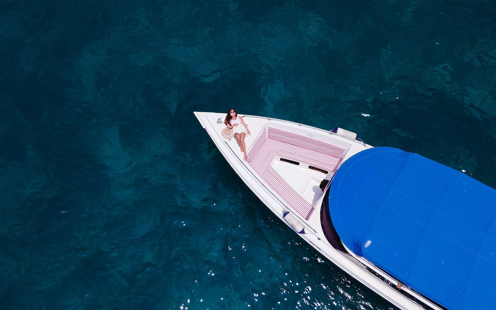 Woman sunbathing on speedboat in clear water near Phi Phi Islands, Thailand.