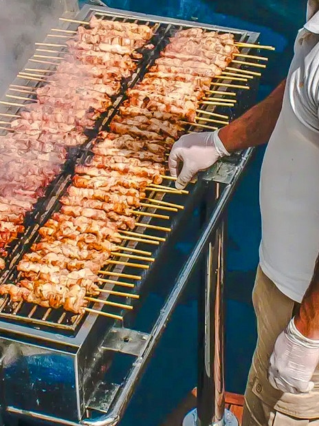 Chef grilling skewers on a catamaran cruise in Santorini.