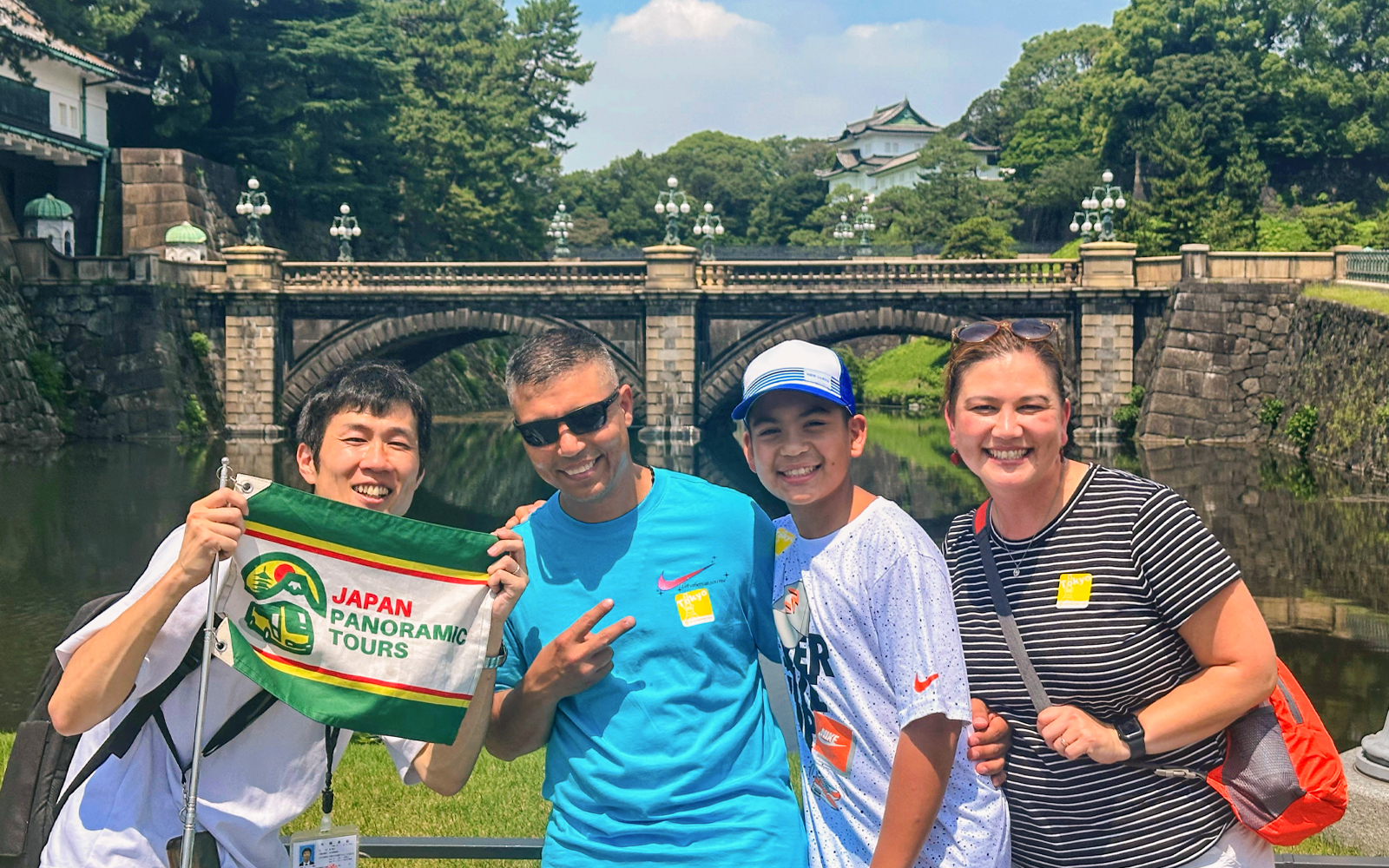 Tour group at Tokyo's Imperial Palace bridge with guide holding tour flag.