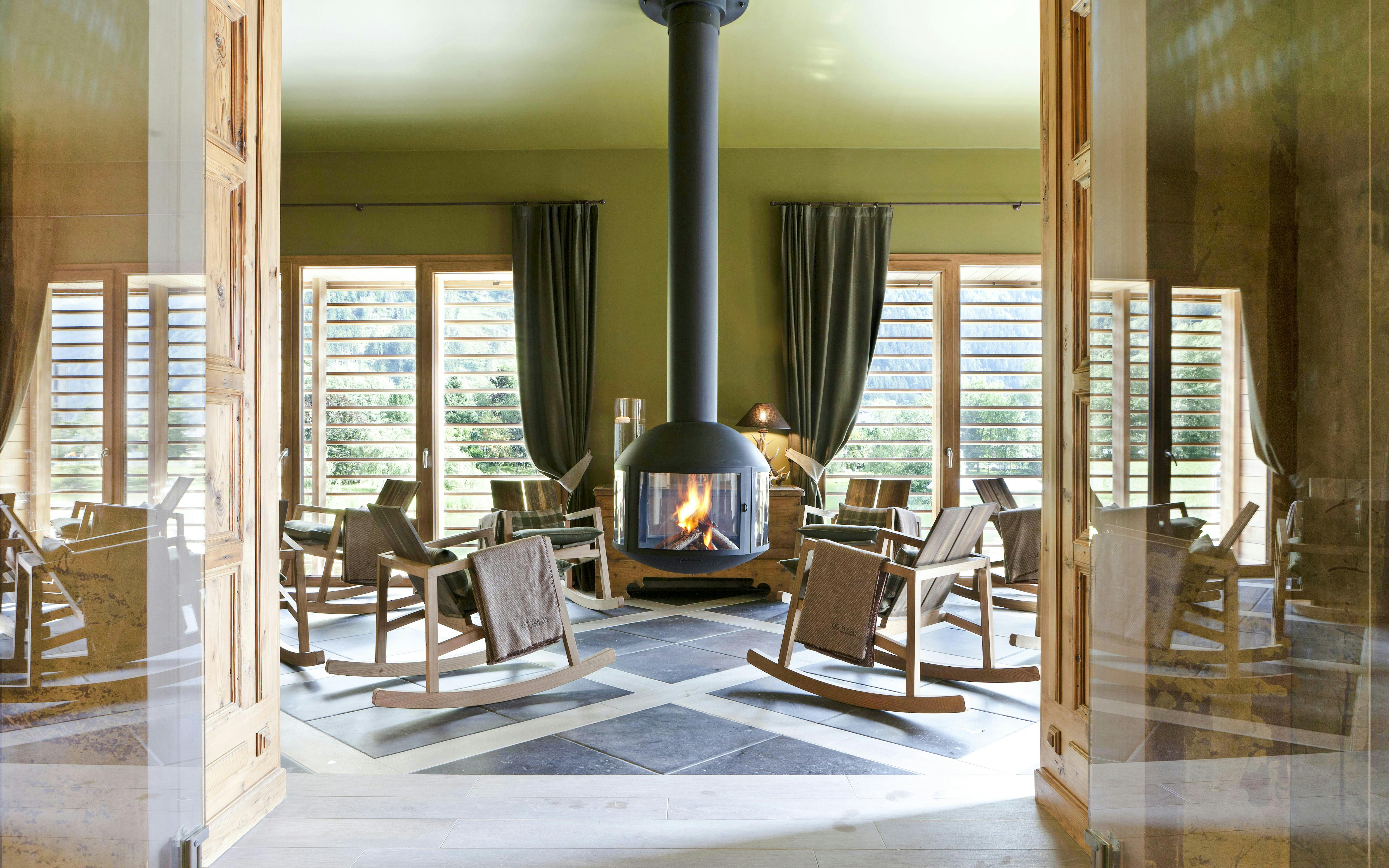 Rocking chairs around a fireplace at QC Terme Chamonix spa with mountain views.