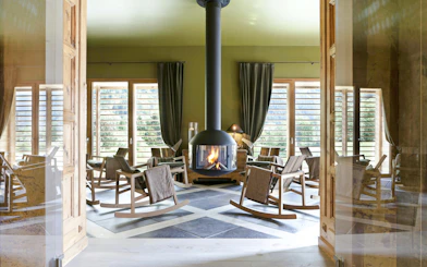 Rocking chairs around a fireplace at QC Terme Chamonix spa with mountain views.