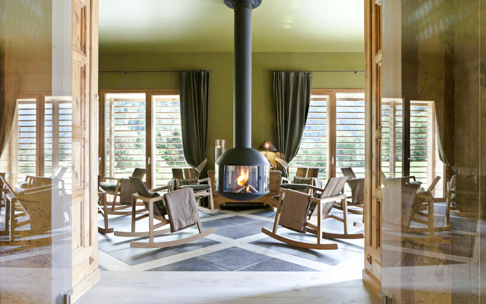 Rocking chairs around a fireplace at QC Terme Chamonix spa with mountain views.