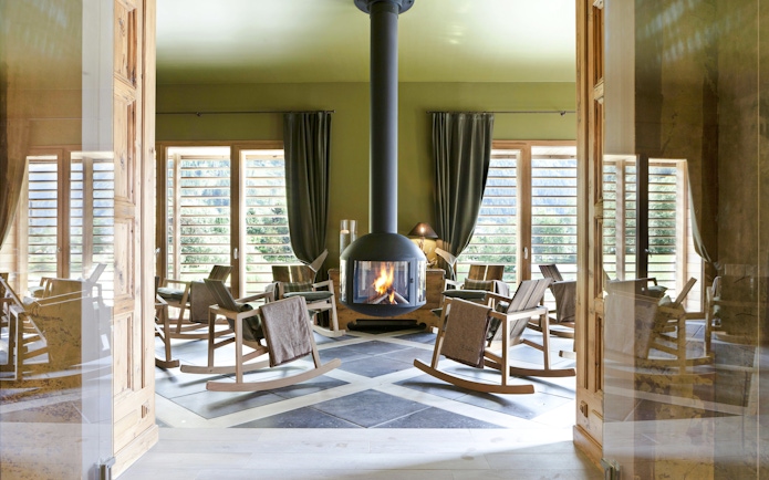 Rocking chairs around a fireplace at QC Terme Chamonix spa with mountain views.