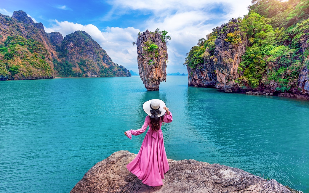 Woman in pink dress on rock at James Bond Island, Phang Nga, Thailand.