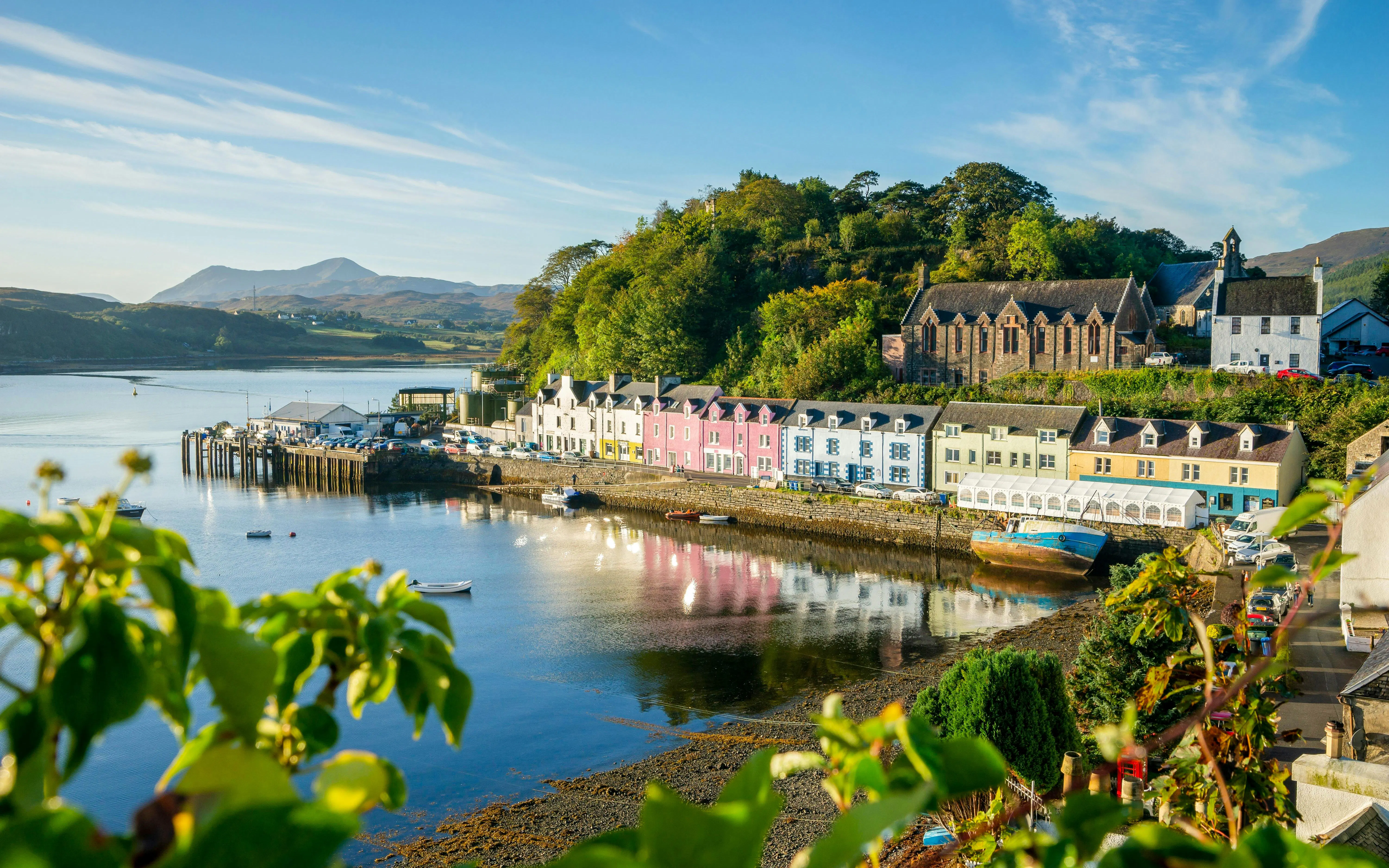 Colorful buildings along the Harbour of Portree, Isle of Skye, with hills in the background.