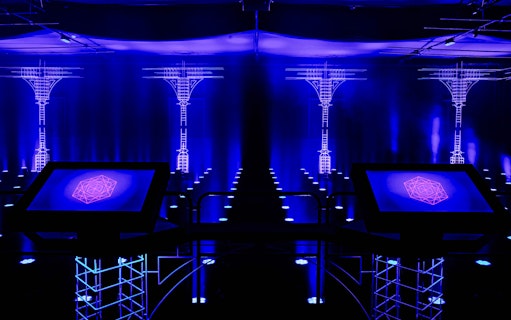 Interactive digital art installation at AMAZE Amsterdam with neon blue lighting.